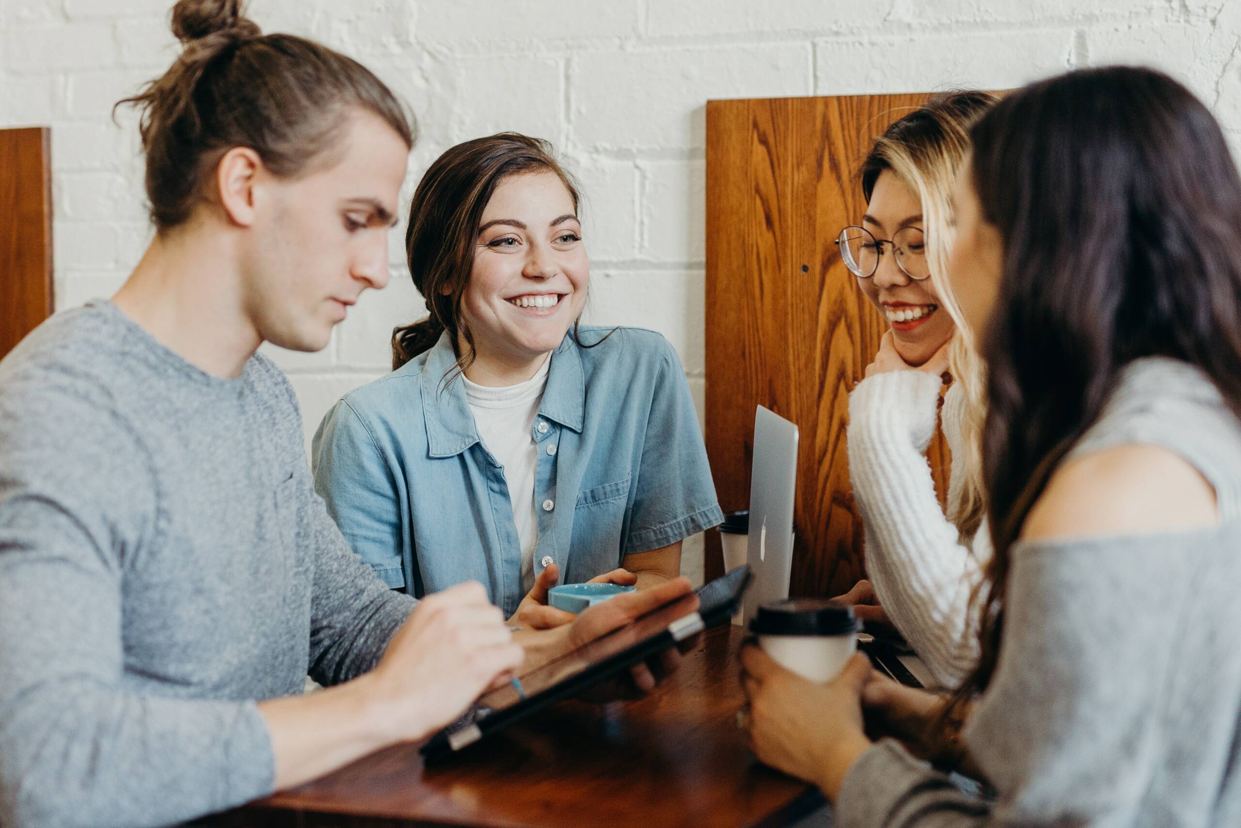 Vier junge Menschen sitzen in Besprechung. Symbolisch für transparente Kommunikation.