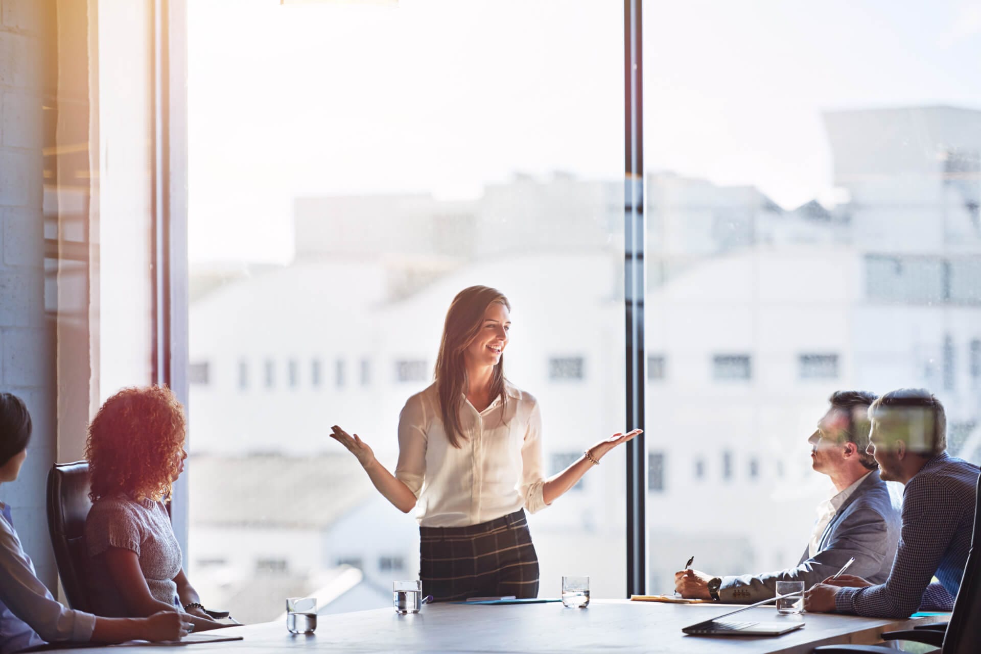 Eine externe Mentorin spricht zu Mitarbeitern eines Unternehmens im Meeting-Raum