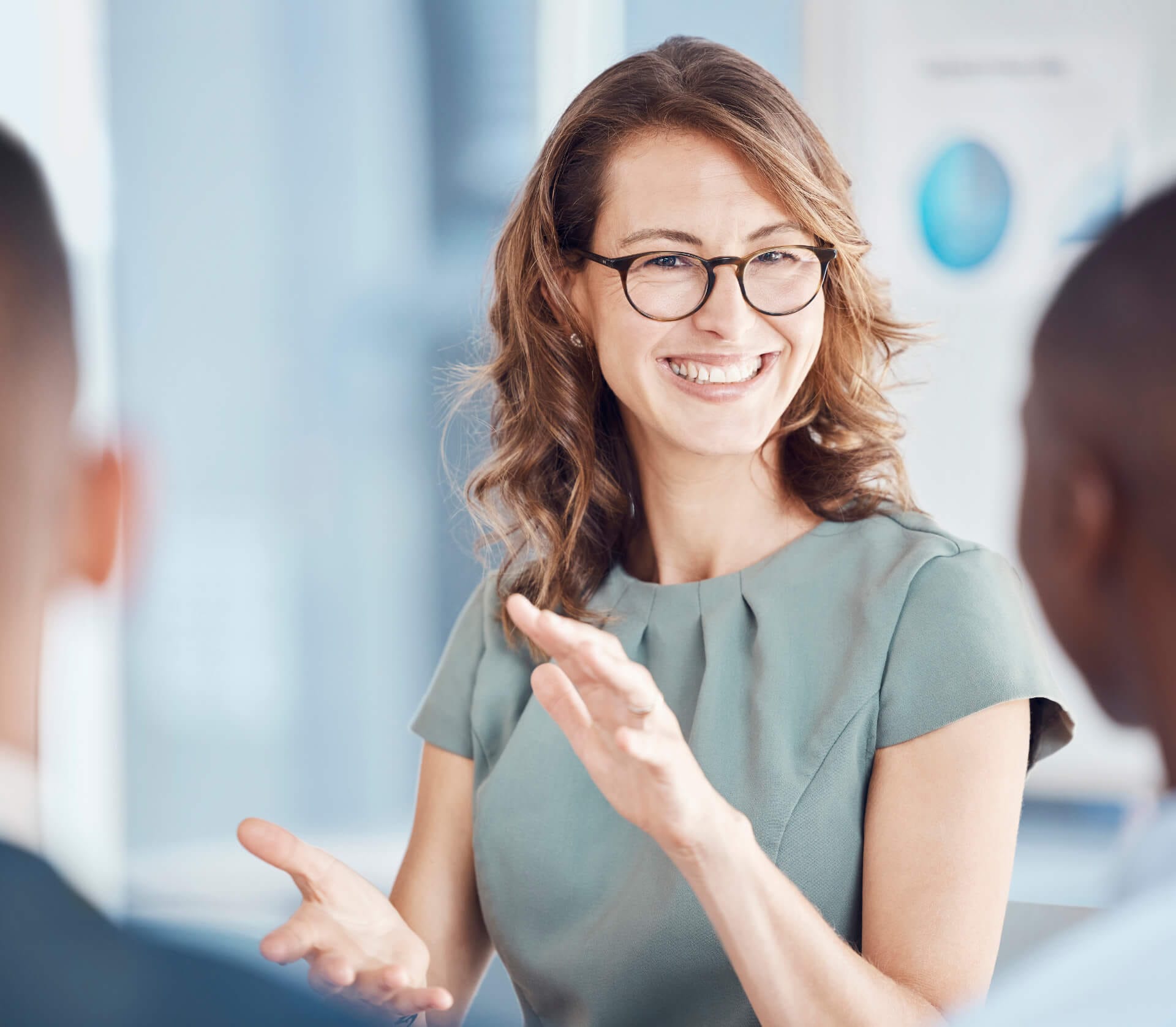 Eine Frau im Gespräch mit zwei Mitarbeitern während einer Coaching Session