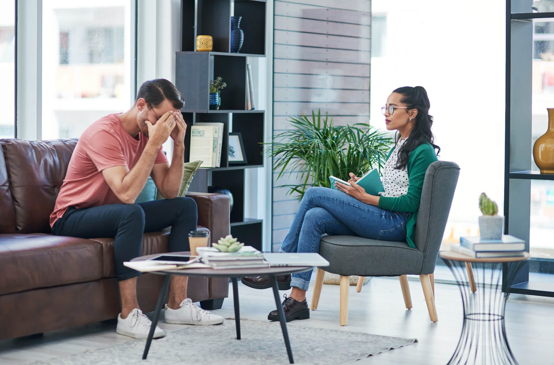 Eine Therapeutin hört einem Patienten während einem psychosoziale Gespräch zu und macht Notizen. Symbolisches Bild für Supervision in helfenden, medizinischen, psychosozialen und pädagogischen Berufen.